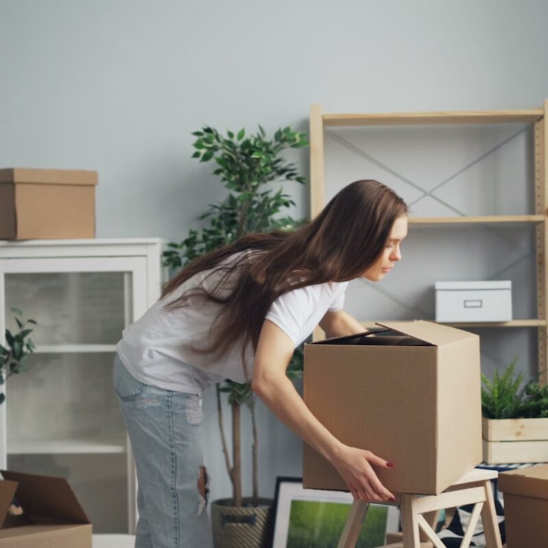 a woman moving boxes in a living room
